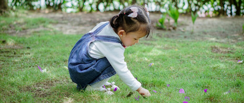 Little girl sitting in the grass playing